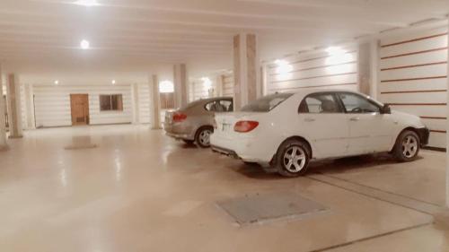 un coche blanco aparcado en un garaje con dos coches en The Lavish Inn en Murree