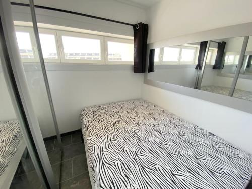 - une chambre avec un lit à motifs zébrés et un miroir dans l'établissement Appartement 88, Port Nature au village naturiste, au Cap d'Agde