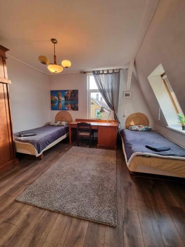 a room with two beds and a desk and a table at Gedimino g. 2 in Mažeikiai