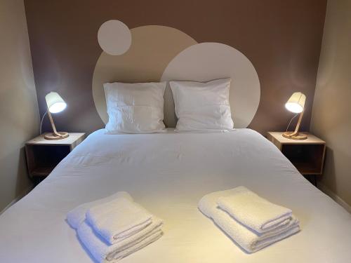 a bedroom with a white bed with two towels on it at Villas de La Ferme Du Gros Noyer in Malaucène