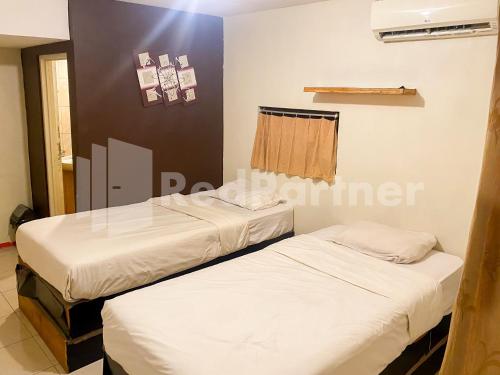 2 camas en una habitación con sábanas blancas en Audah Guesthouse Syariah Kuningan RedPartner, en Yakarta