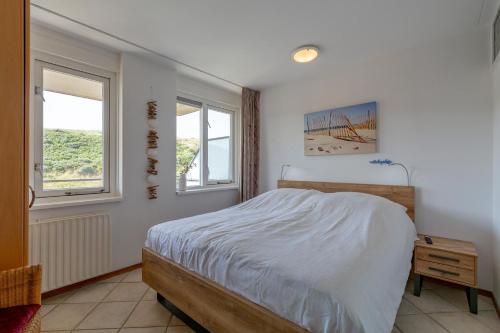 een slaapkamer met een bed en 2 ramen bij Wijde Blick appartement 211 - Callantsoog in Callantsoog