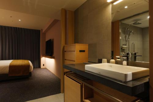 a bathroom with a sink and a bed and a tub at Mitsui Garden Hotel Kyoto Sanjo PREMIER in Kyoto