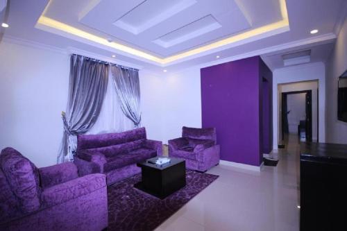 uma sala de estar com cadeiras roxas e uma mesa em اجنحة أروى سويتس الدمام Arwa Suites Dammam em Dammam