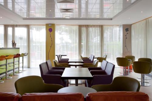 a waiting room with chairs and tables and windows at Holiday Inn Express Paris-Canal De La Villette by IHG in Paris