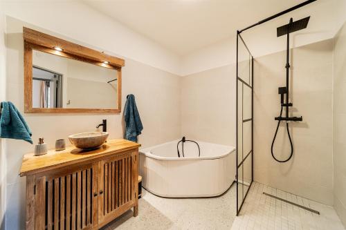 y baño con bañera, lavabo y espejo. en L'éclat tropical, magnifique T3 sur front de mer, en Saint-Pierre
