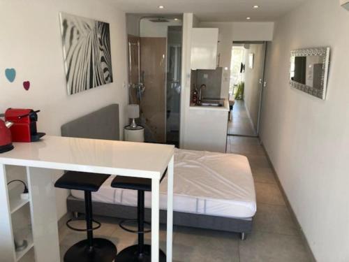 Cette chambre comprend un lit, une table blanche et des tabourets. dans l'établissement Studio 20, Port Nature 2 au village naturiste, au Cap d'Agde
