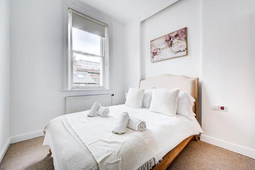 a white bedroom with a bed with towels on it at Duplex Apartment Shoreditch - the Living Elite Collection in London