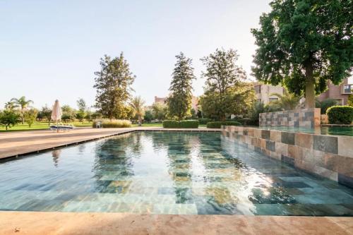 - une piscine dans une cour avec des arbres et des bâtiments dans l'établissement Appartement de Luxe à Marrakech!, à Marrakech