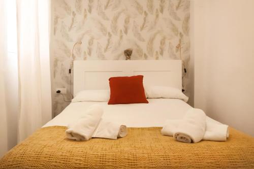 a bedroom with a white bed with a red pillow at Apartamento Alfaqueque in Seville