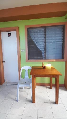 a table and a chair in a room with a door at Reynaldo's Upstairs in Puerto Galera