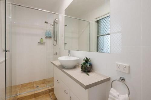 a white bathroom with a sink and a shower at Yaringa Noosa Heads - Ocean View, Walk to Beach in Noosa Heads