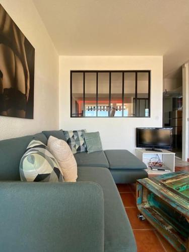 un salon avec un canapé bleu et une télévision dans l'établissement Studio 535, Port Nature 5 au village naturiste, au Cap d'Agde