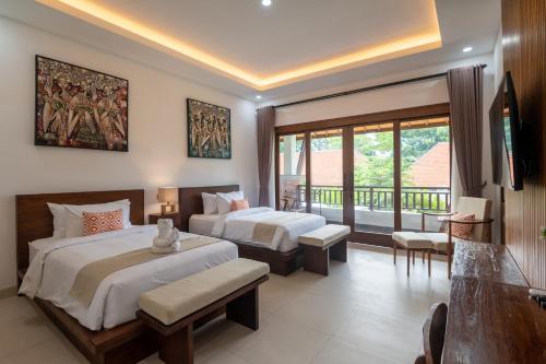 a hotel room with two beds and a balcony at Griya Shanti Suites in Sanur