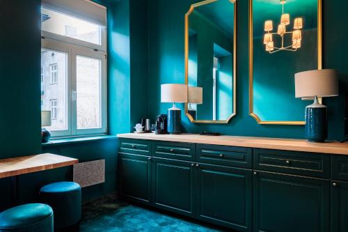 een badkamer met blauwe muren en een wastafel met spiegels bij Green Gertrudy in Krakau