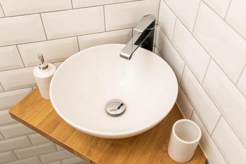 a white sink in a bathroom with white tiles at Apartman 114 in Baška