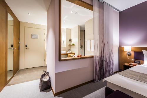 a hotel room with a bed and a mirror at Deltapark Vitalresort**** in Thun