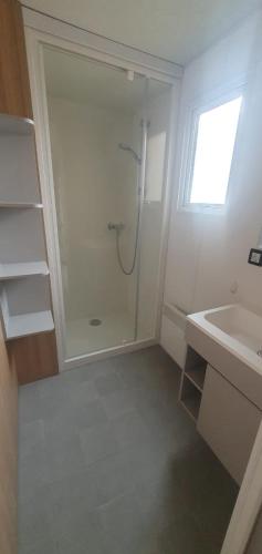 une salle de bain blanche avec une douche et un lavabo dans l'établissement Mobile home à Mimizan géré par un particulier, à Mimizan