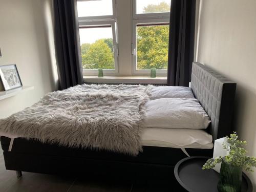 una cama con una manta peluda junto a una ventana en Ferienwohnung PIER 2 in Cuxhaven, en Cuxhaven