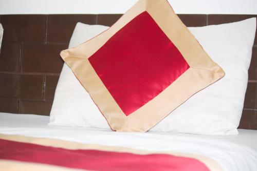 cuscino rosso posto sopra un letto di Hotel Glass House a Kāta Patthar