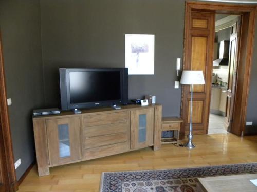 una sala de estar con TV en un centro de entretenimiento de madera en Lovely Bourg house 4 pers 2 bedr 2 bath Wifi en Charleroi