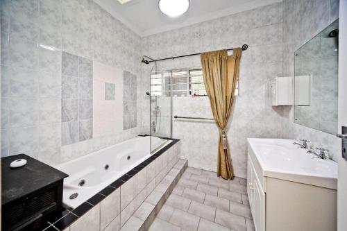 un baño con bañera y lavabo en Cozy oasis on Derby, en Johannesburgo