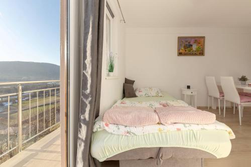 1 dormitorio con 1 cama y balcón con vistas. en Zidanica med Trtami, en Dvor