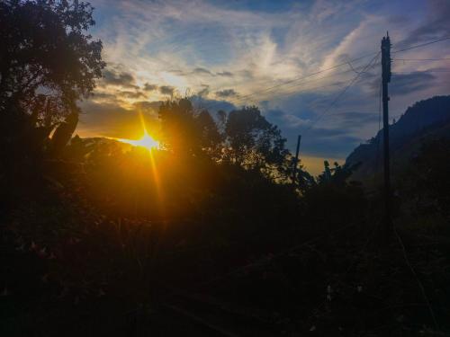 a sunset with the sun shining through the trees at Ella Happy View Homestay in Ella