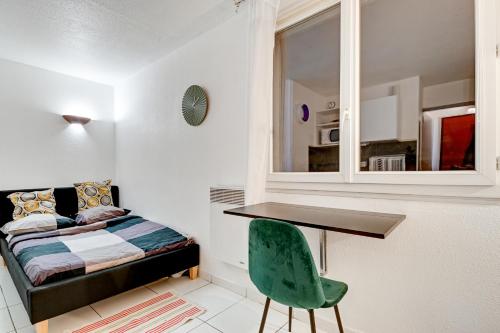 a bedroom with a bed and a desk and a green chair at Budget Studio with parking in Cergy