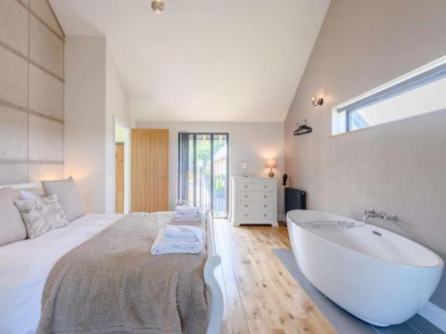 ein Schlafzimmer mit großem Bett und Badewanne in der Unterkunft Romantic cottage for 2 with hot tub in Wimborne Minster
