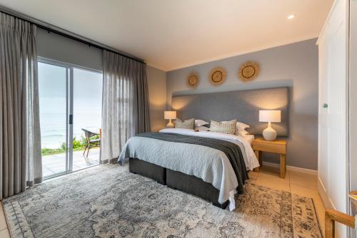 a bedroom with a bed and a large window at Mes Amis Beach Guest House in Wilderness