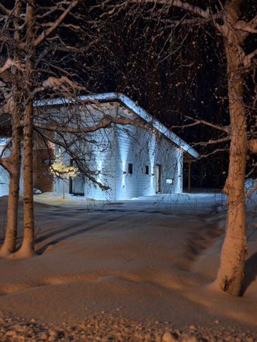 a white barn with snow on it at night at Villa Arctic Light in Rovaniemi