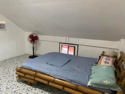 uma cama num quarto com uma ventoinha vermelha em Koa's Beach House em Tangalan