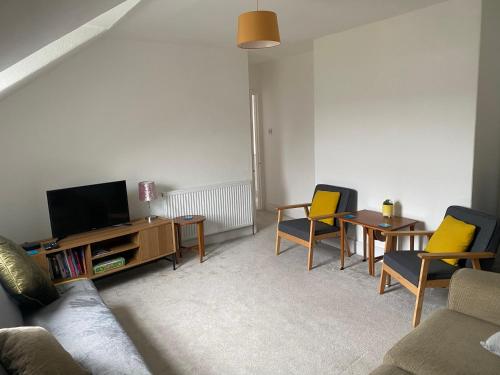 ein Wohnzimmer mit einem Sofa, Stühlen und einem TV in der Unterkunft Lovely 2 Bedroom Loft Apartment in Buxton in Buxton