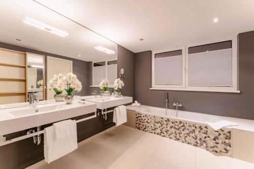 a bathroom with two sinks and two mirrors at PLAZA INN Graz in Graz