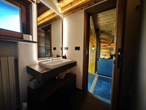 a bathroom with a sink and a mirror and a door at Hostdomus - Chalet Sun in Sestriere