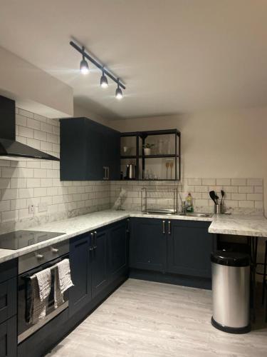 una cucina con armadi blu e pareti in piastrelle bianche di MODERN APARTMENT-GREENWICH/WOOLWICH a Woolwich