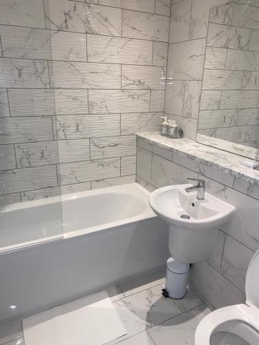 La salle de bains est pourvue d'un lavabo, d'une baignoire et de toilettes. dans l'établissement MODERN APARTMENT-GREENWICH/WOOLWICH, à Woolwich