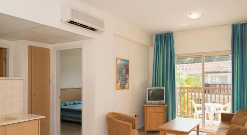 a living room with a couch and a tv in it at Tsokkos Paradise Holiday Village in Ayia Napa