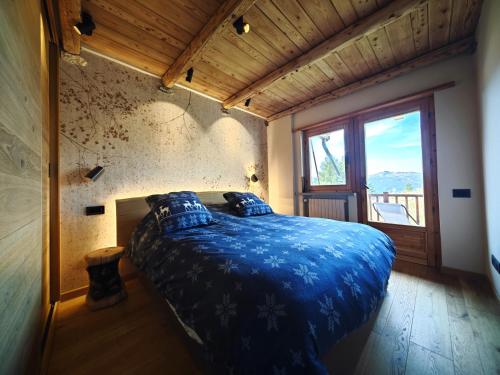 a bedroom with a blue bed in a room with a window at Hostdomus - Chalet Sun in Sestriere