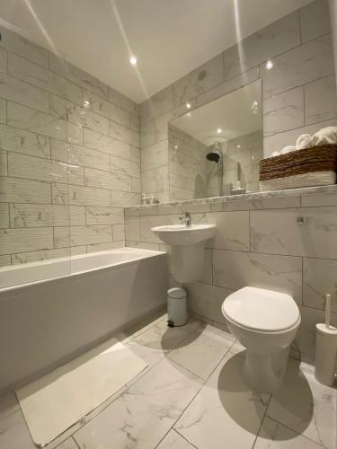 La salle de bains blanche est pourvue de toilettes, d'une baignoire et d'un lavabo. dans l'établissement MODERN APARTMENT-GREENWICH/WOOLWICH, à Woolwich