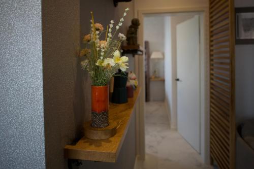 a vase with flowers on a shelf in a hallway at 36 Phô Cô Hotel & Suites in Weimar