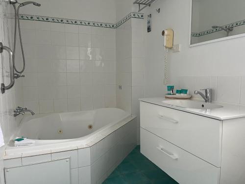 a white bathroom with a tub and a sink at Diamond Beach Holiday Park in Diamond Beach