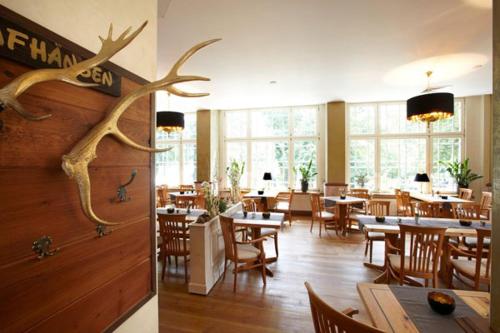a restaurant with tables and chairs and antlers on the wall at Idyll Am Wolgastsee in Korswandt