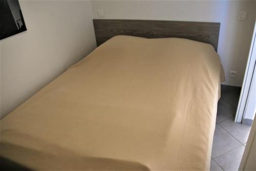 Ce lit se trouve dans une petite chambre dotée d'un couvre-lit. dans l'établissement Appart 486, Port nature 4 au village naturiste, au Cap d'Agde