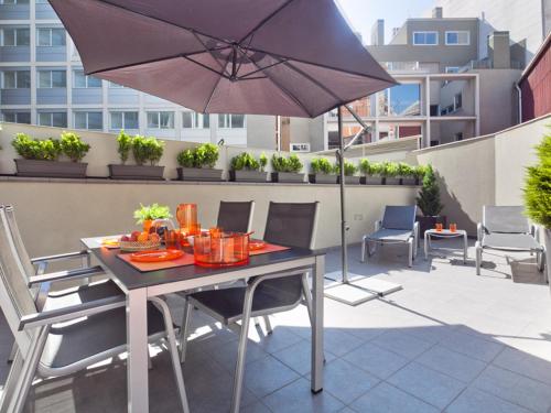 a table and chairs with an umbrella on a balcony at Charmsuites Paralel in Barcelona