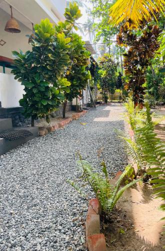 a gravel pathway with trees and plants next to a building at Cliff & Coral in Varkala