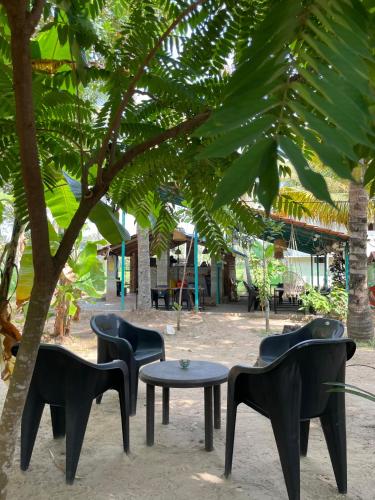 a group of chairs and a table under a tree at Cliff & Coral in Varkala