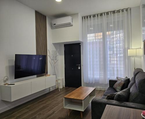 een woonkamer met een bank en een flatscreen-tv bij El Tesoro de la Mezquita in Córdoba