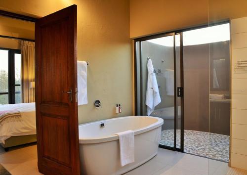 ein Bad mit einer Badewanne, einem Bett und einer Dusche in der Unterkunft Mjejane Luxury Self-Catering Villa in Hectorspruit